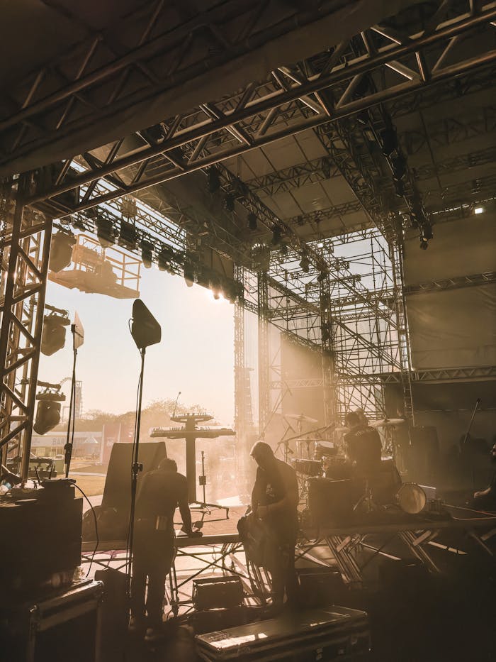 Silhouette of musicians preparing on stage for a live music performance during sunset.