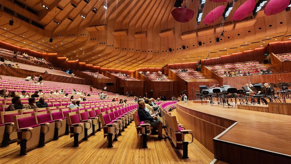 Spacious interior view of Sydney Opera House concert hall with seating and stage.