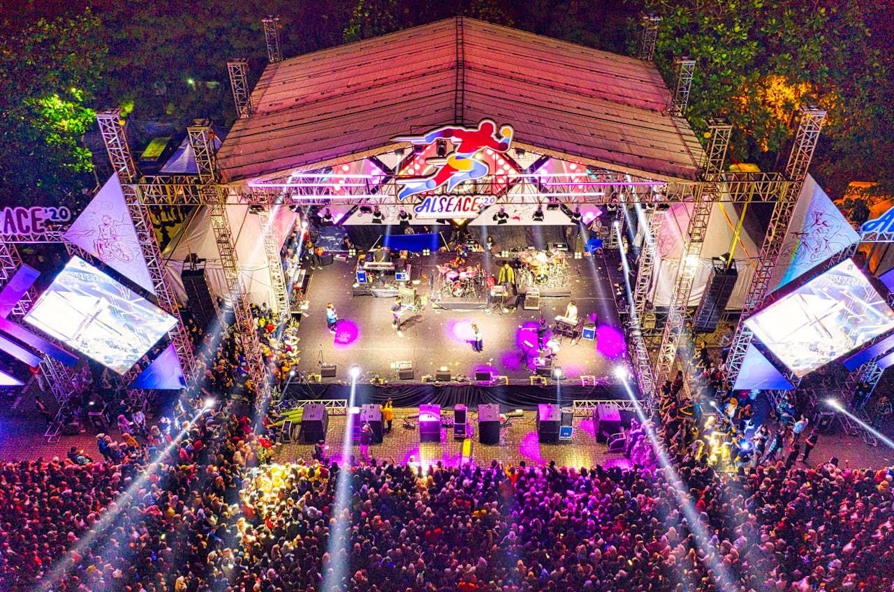 Aerial view of a lively outdoor concert in Banten, Indonesia with colorful stage lights.