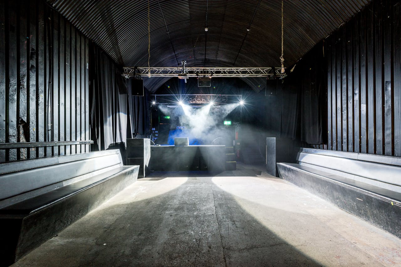 A deserted nightclub featuring stage lighting and seating, highlighting its industrial design.